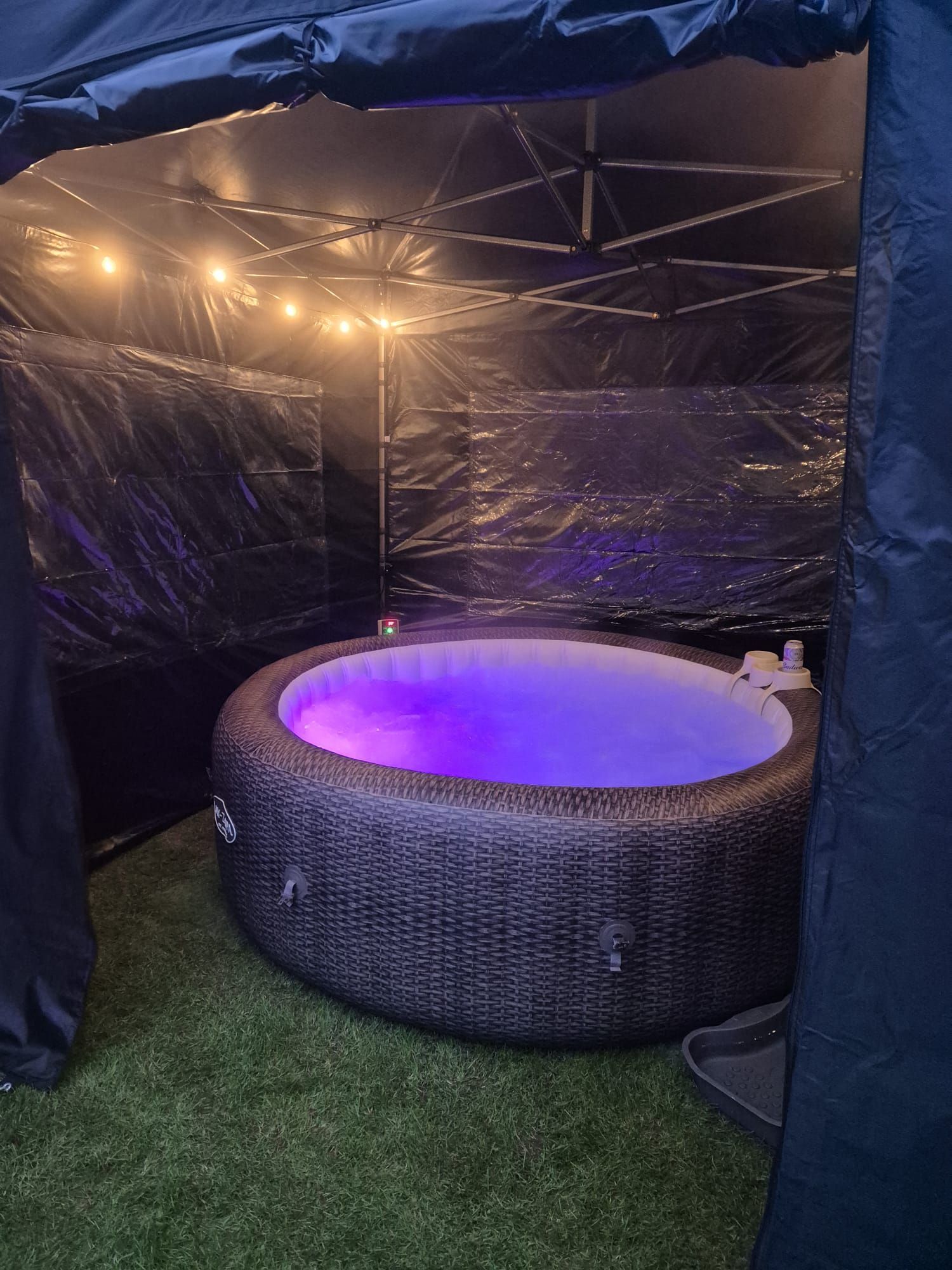A hot tub with purple lights inside of a tent.