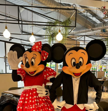 A couple of mickey mouse mascots standing next to each other