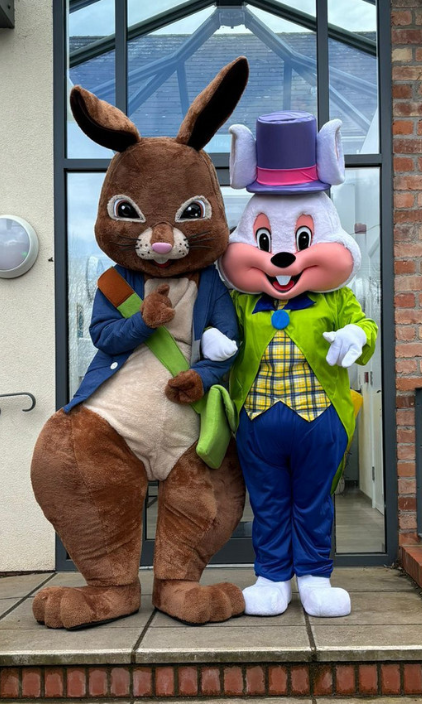 Two mascots are standing next to each other in front of a building