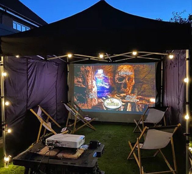 A projector is sitting on a table in front of a large screen.