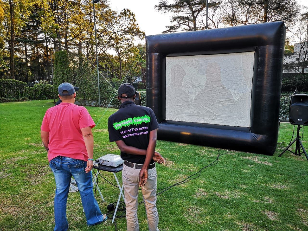 Two men are standing in front of a large inflatable screen.