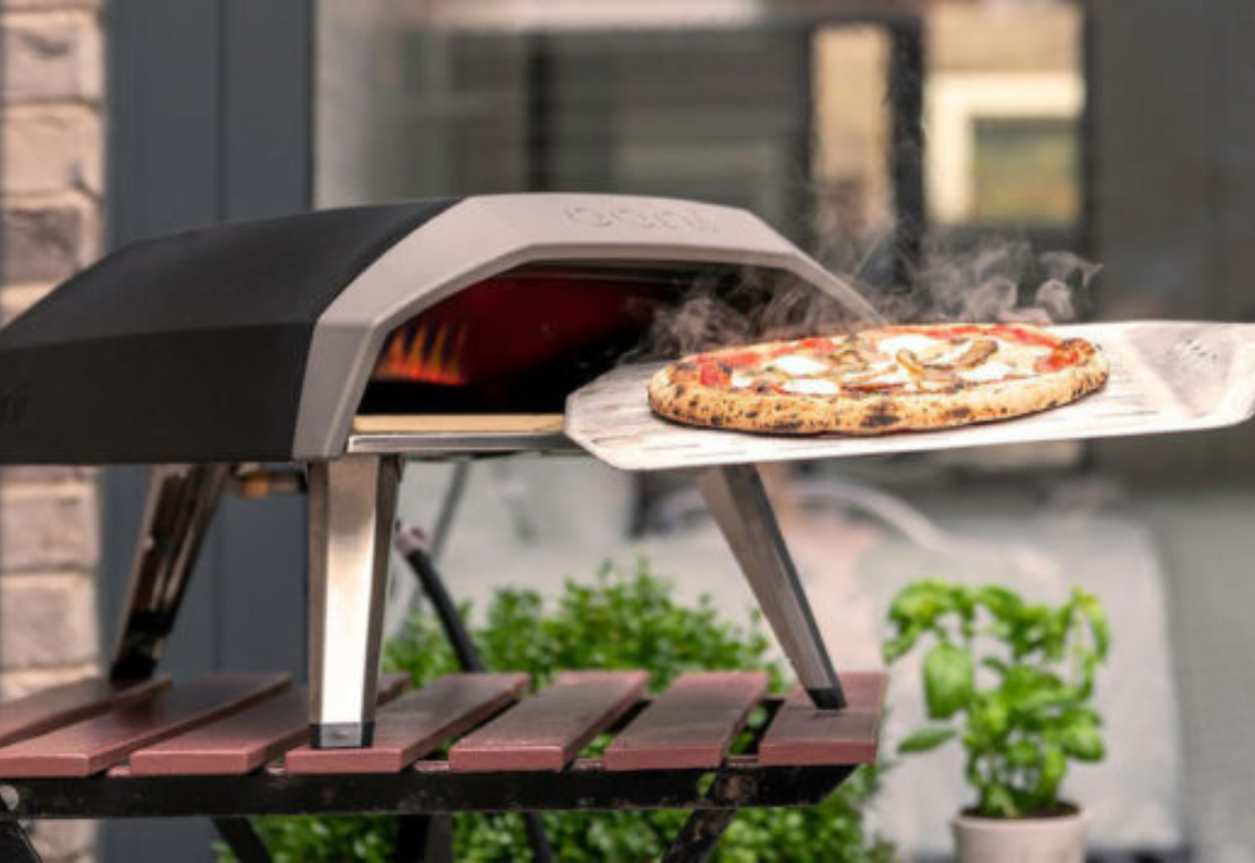 A pizza is being taken out of a pizza oven on a table.