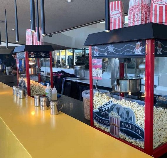 A row of popcorn machines are lined up on a counter