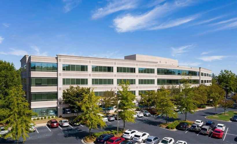A large office building with a lot of cars parked in front of it.