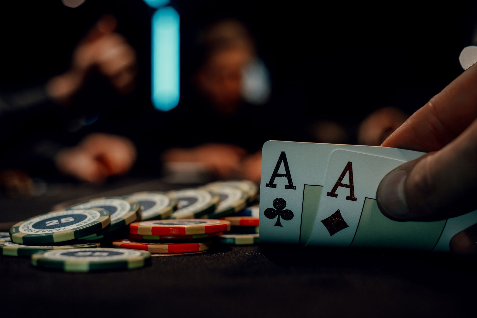 A player holds two aces over a table stacked with colorful poker chips.
