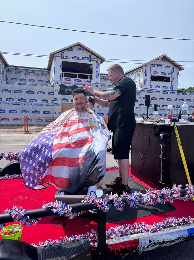 Person getting a patriotic red, white, and blue haircut outdoors on a decorated float