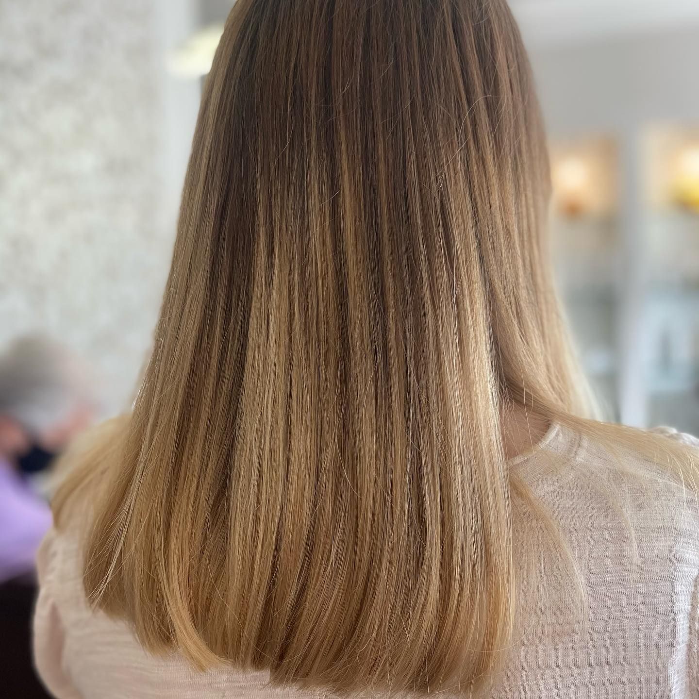 Woman with crimped ombre hair, from dark to light blonde, wearing a light-colored top.