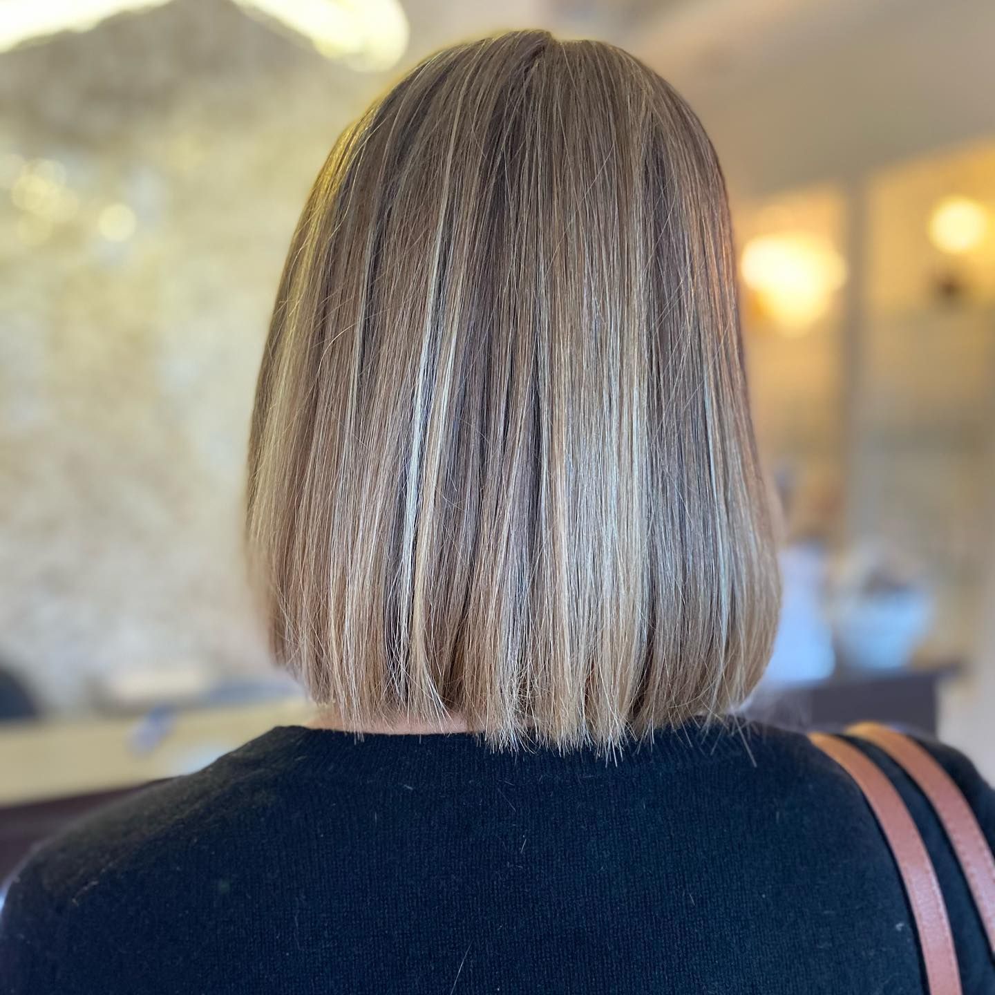 Woman with a short, crimped hairstyle. The hair is light brown with highlights. Seen from the back.