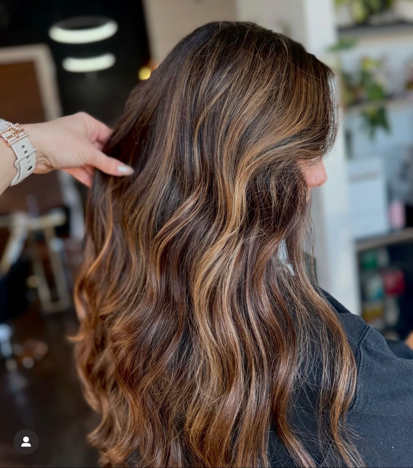 Wavy brown hair with highlights, being styled in a salon.