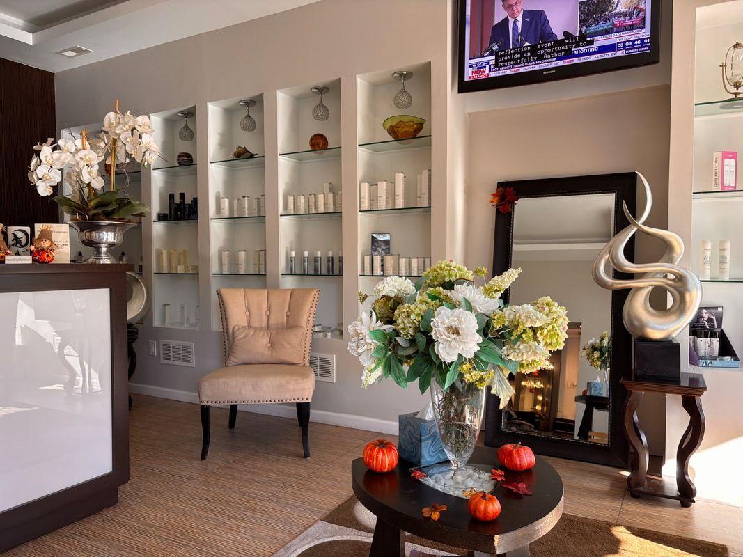 Spa reception area with shelves of products, a chair, and floral arrangements.