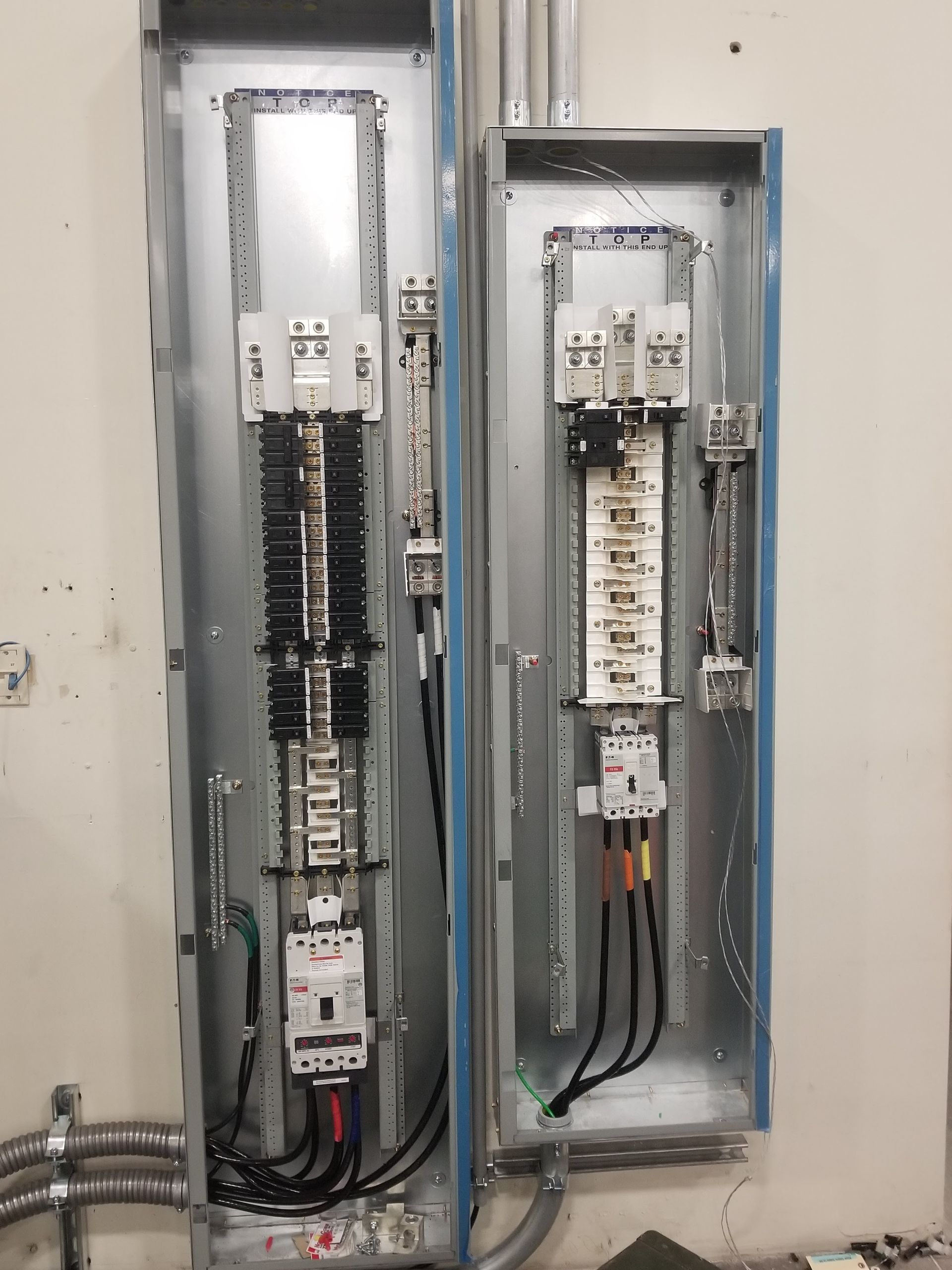 Electrical panels mounted on a wall with wiring and circuit breakers visible.