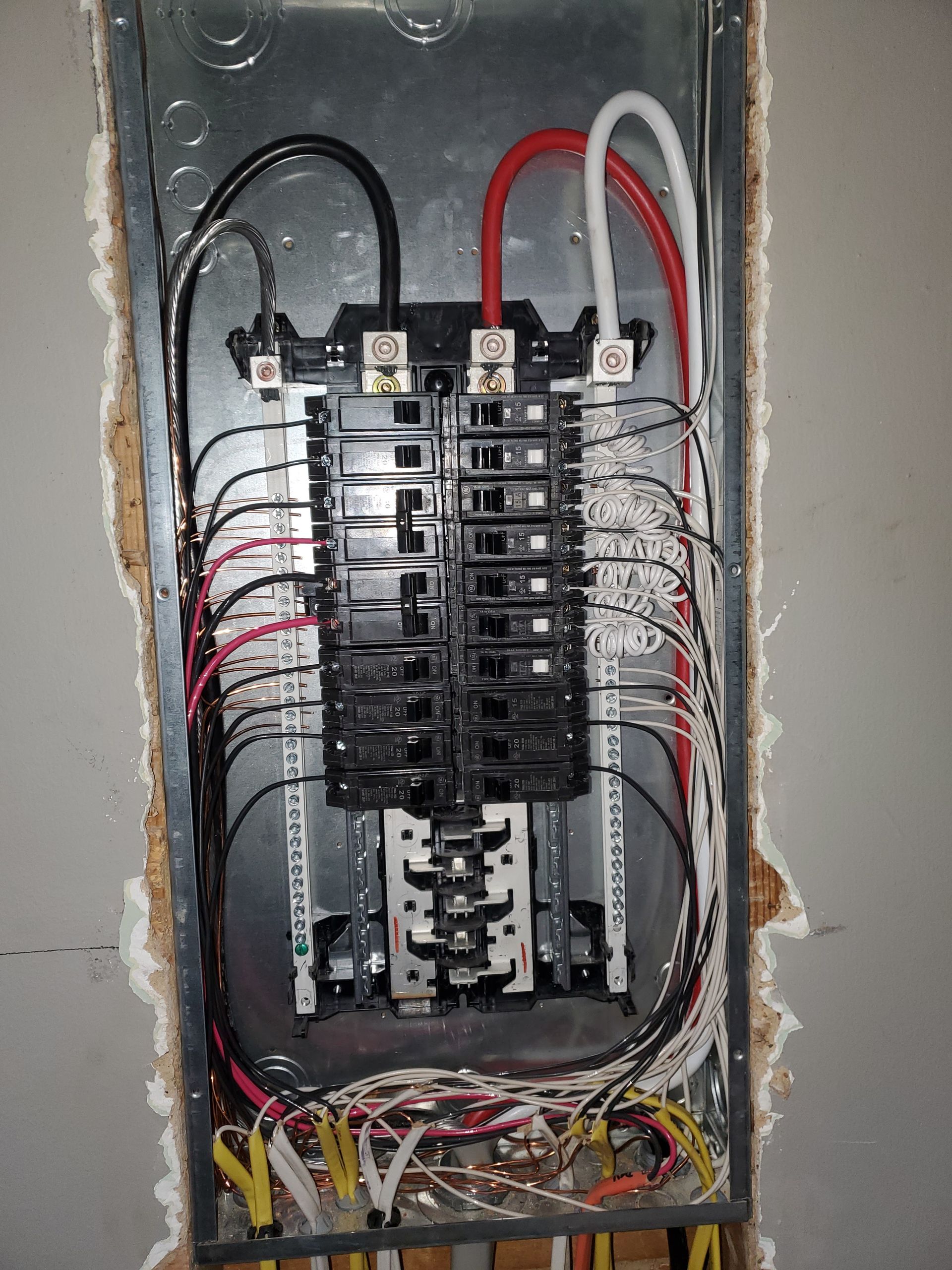 Electrical panel with wires of various colors, mounted in a wall.