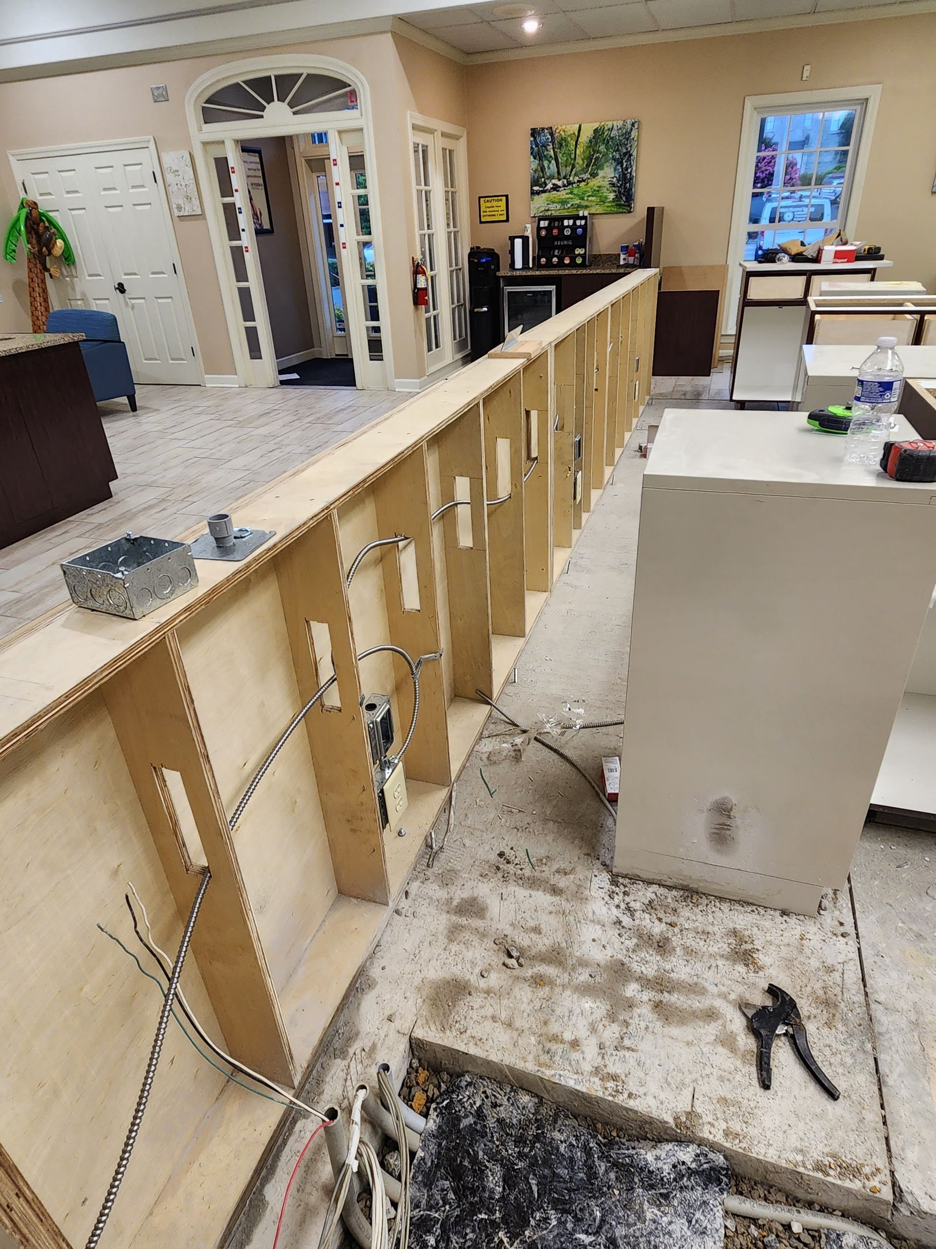 Wooden framework for a counter under construction, with electrical wires and tools. Interior setting.