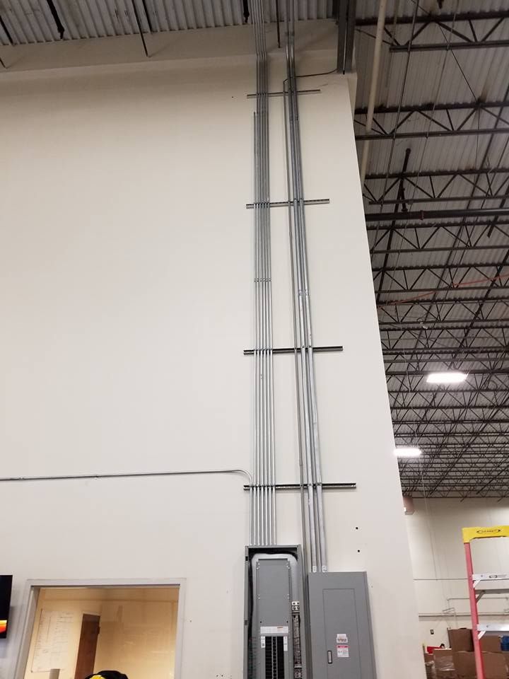 Electrical conduit and panels mounted on a white wall in a commercial building.