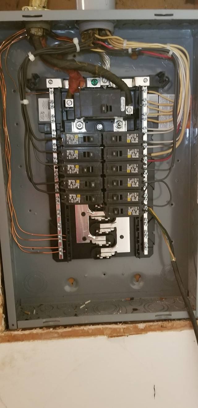 Electrical panel with circuit breakers and wiring. Gray metal box mounted on a wall.
