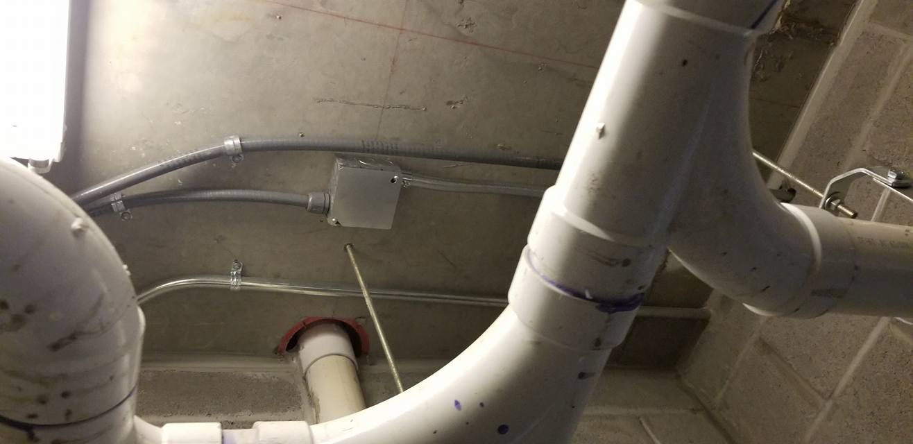 White PVC pipes and electrical conduit run across a concrete ceiling.