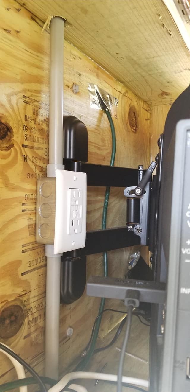 Electrical components mounted inside a wooden enclosure. Includes conduit, a light switch, and a black mounting bracket.