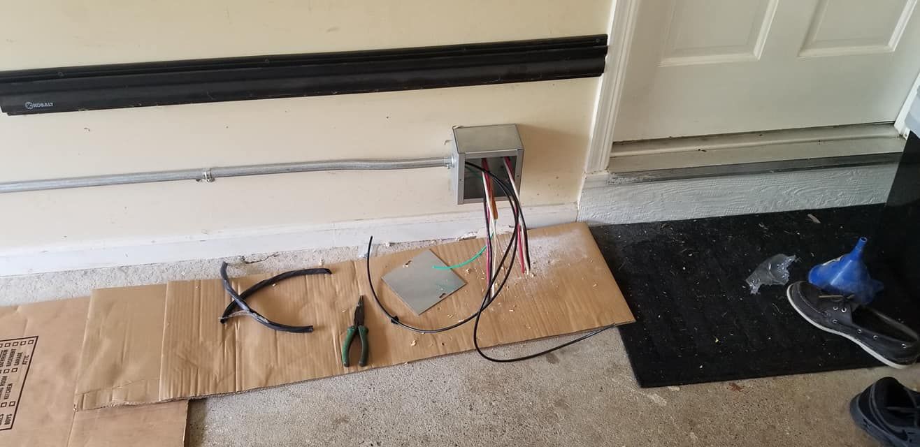 Electrical work in progress: wires, tools, and metal box on a cardboard sheet near a door.