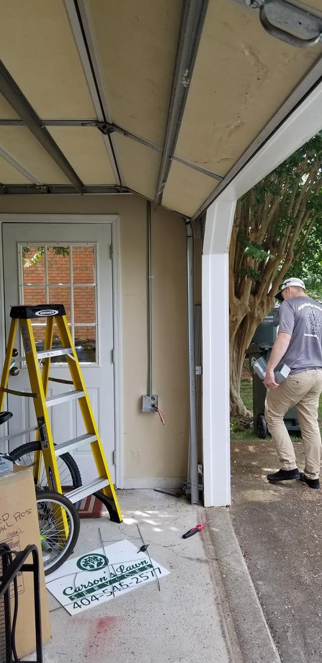 A garage with a ladder, an open door, and two people walking outside.