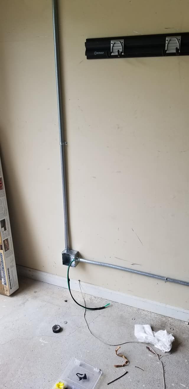 Electrical conduit installed on a light beige wall; a black box is mounted on the wall.