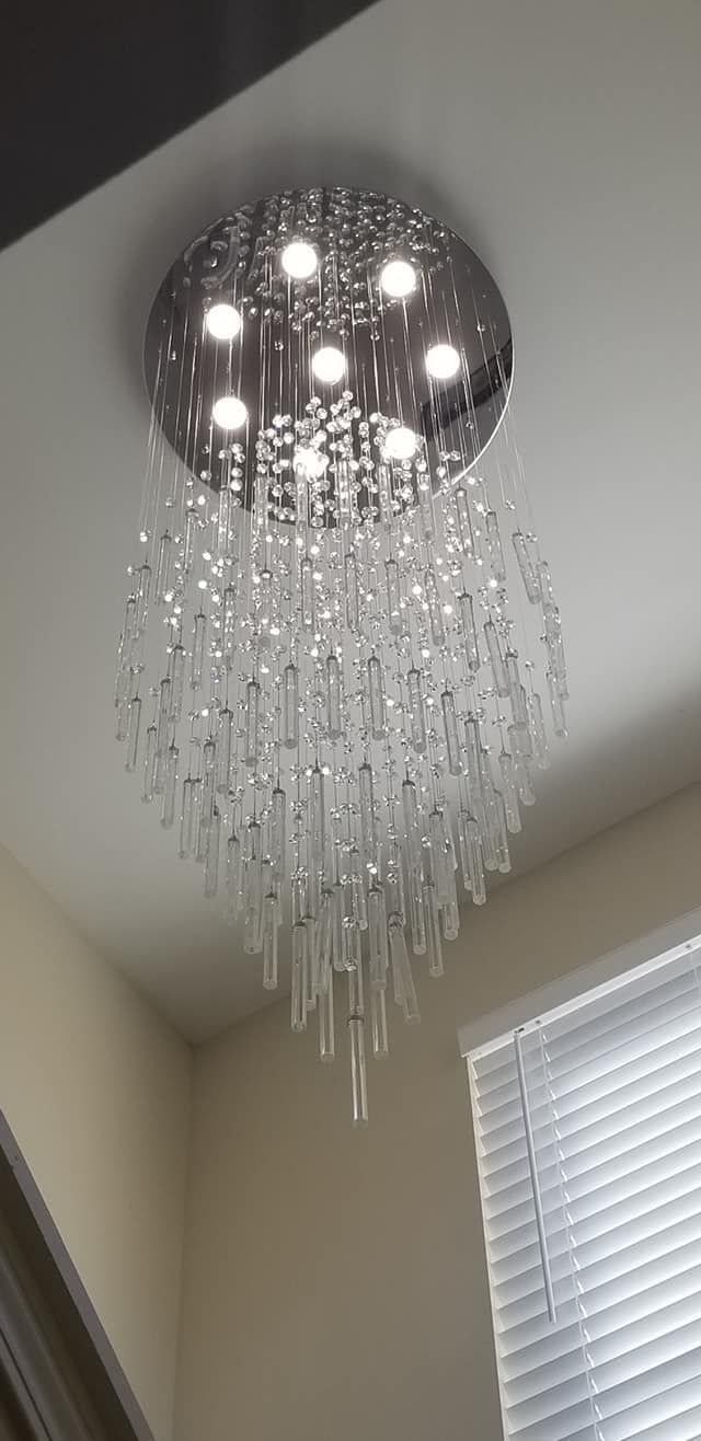 A modern chandelier with multiple hanging glass rods, mounted on a ceiling.