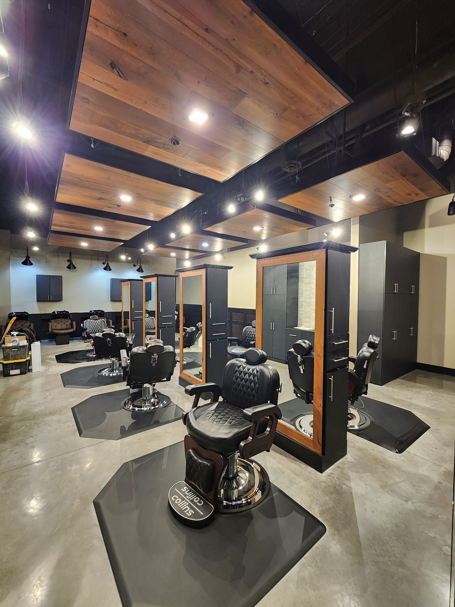 Barber shop interior with stations, chairs, mirrors, and wooden ceiling panels.
