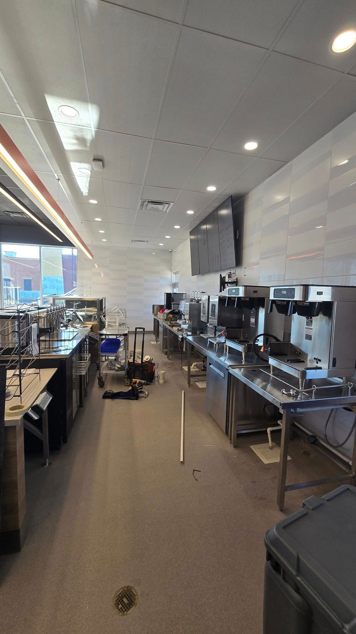 Interior view of a commercial kitchen with stainless steel appliances and white walls.
