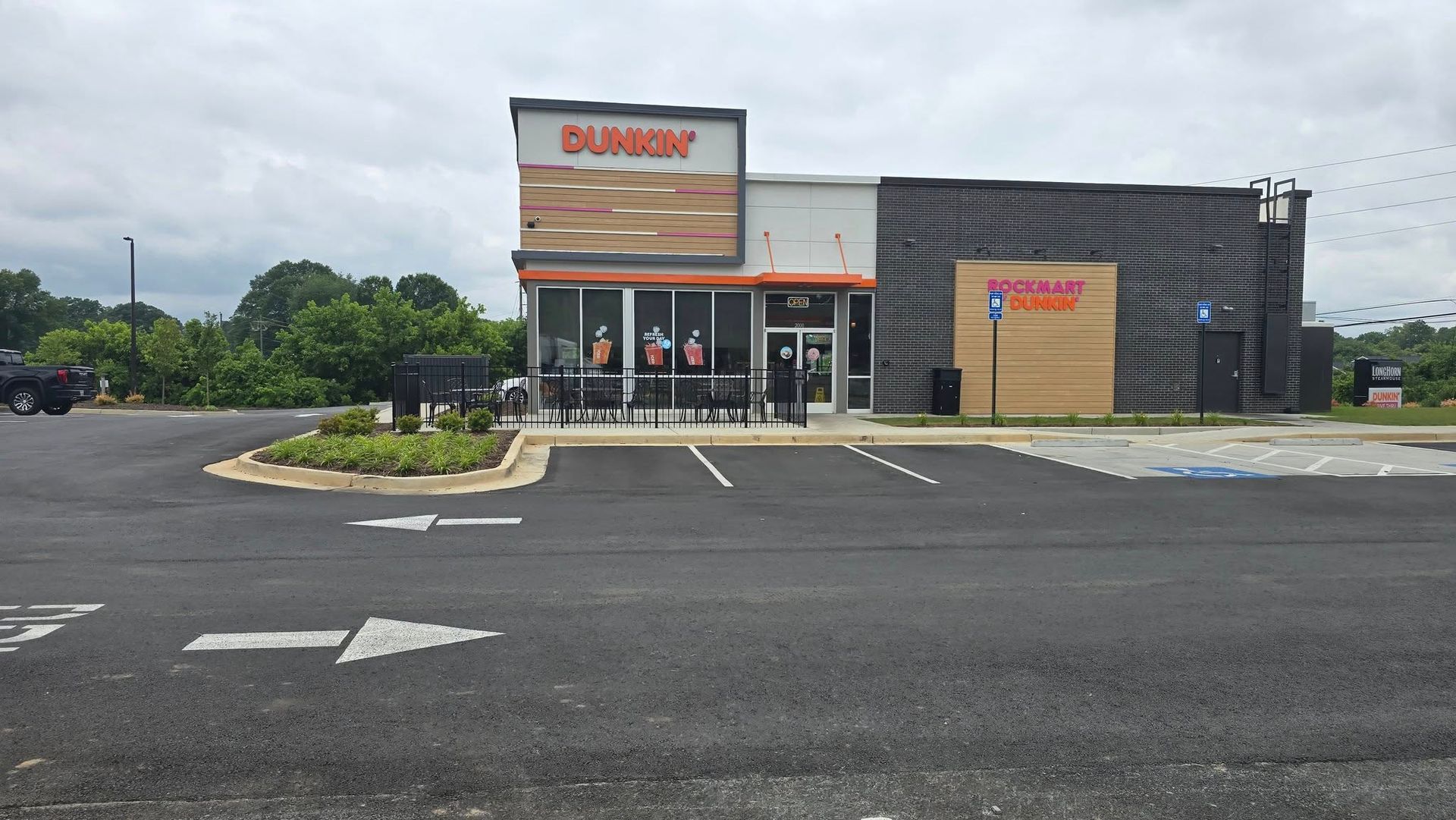 Exterior of a Dunkin' Donuts restaurant with parking spaces, overcast sky.