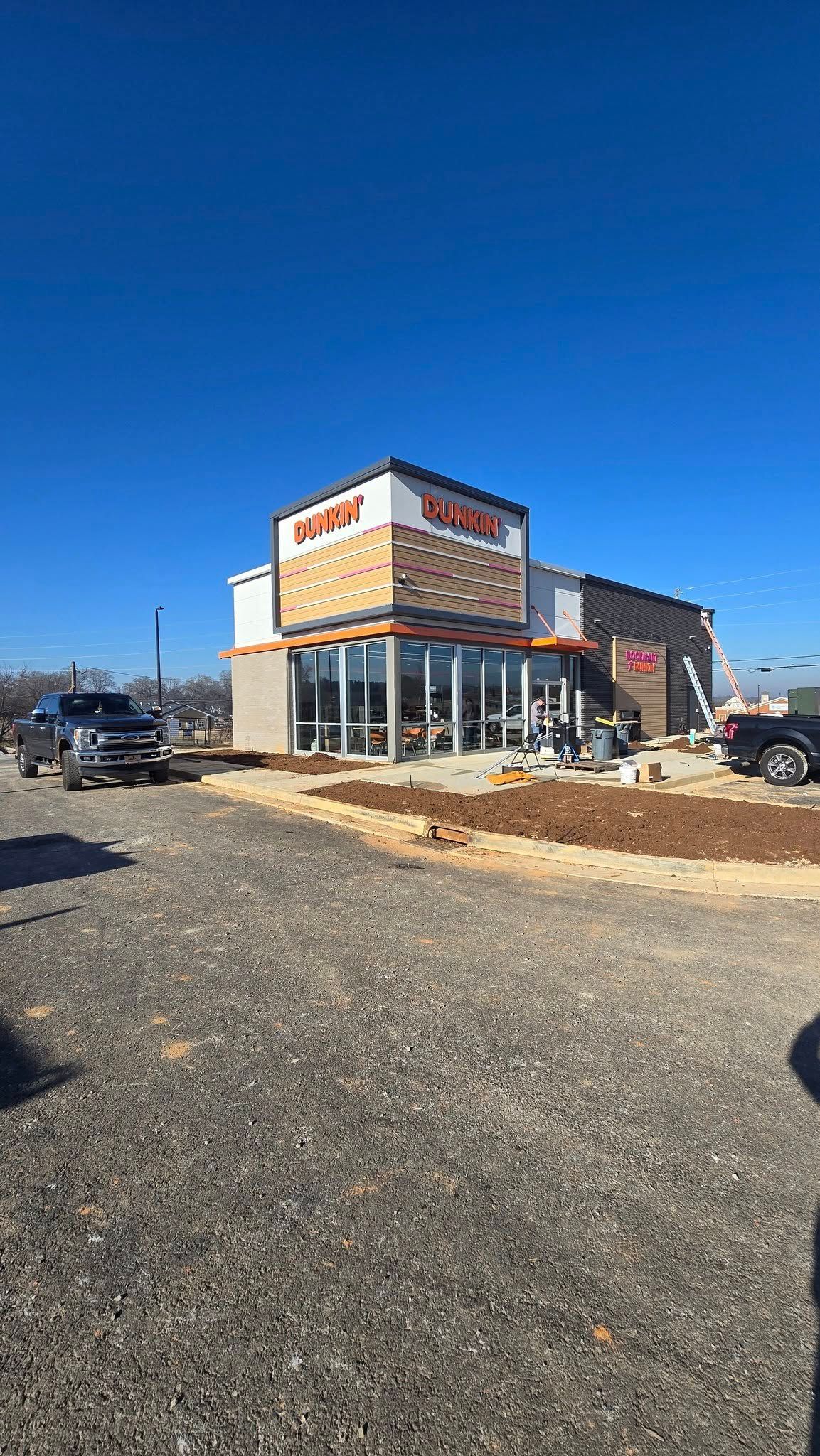 New Dunkin' Donuts under construction on a sunny day with blue sky; gravel drive.