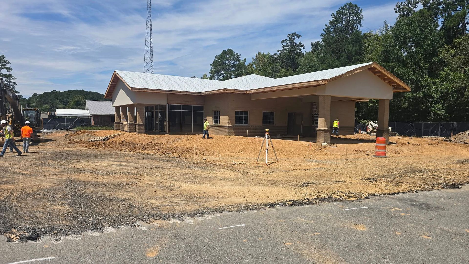 Construction site with a partially built building; brown dirt ground; blue sky.