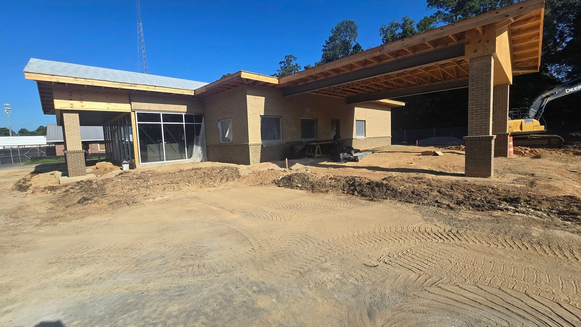 Building under construction with a covered entrance, set on a dirt lot.