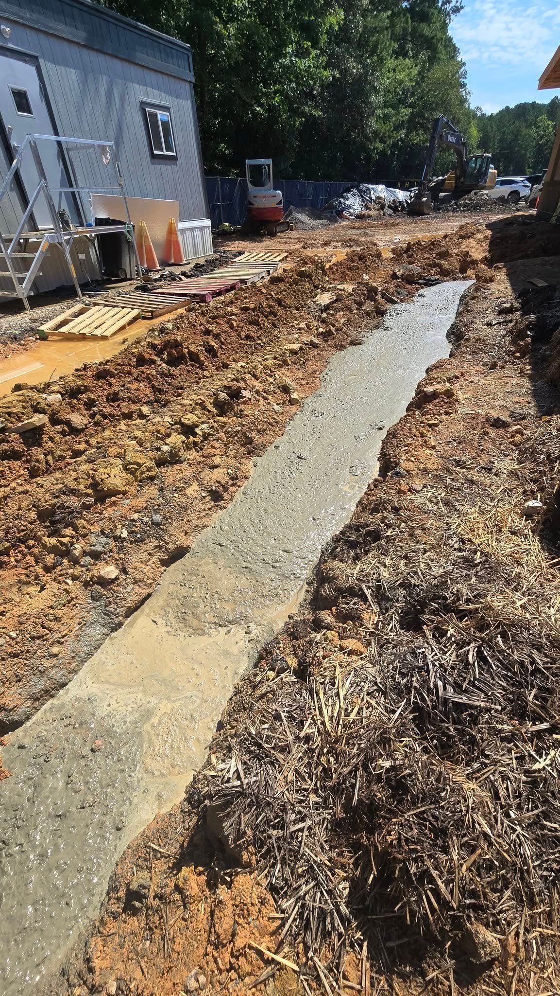 A long concrete path is freshly poured in a construction site with dirt and equipment visible.