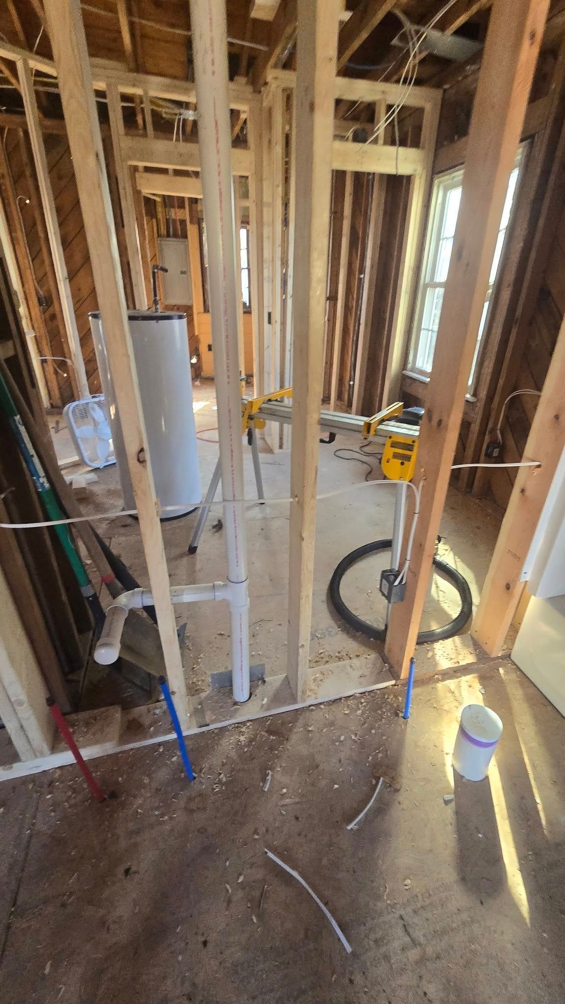 Interior view of a bathroom under construction with exposed wooden framing and plumbing fixtures.
