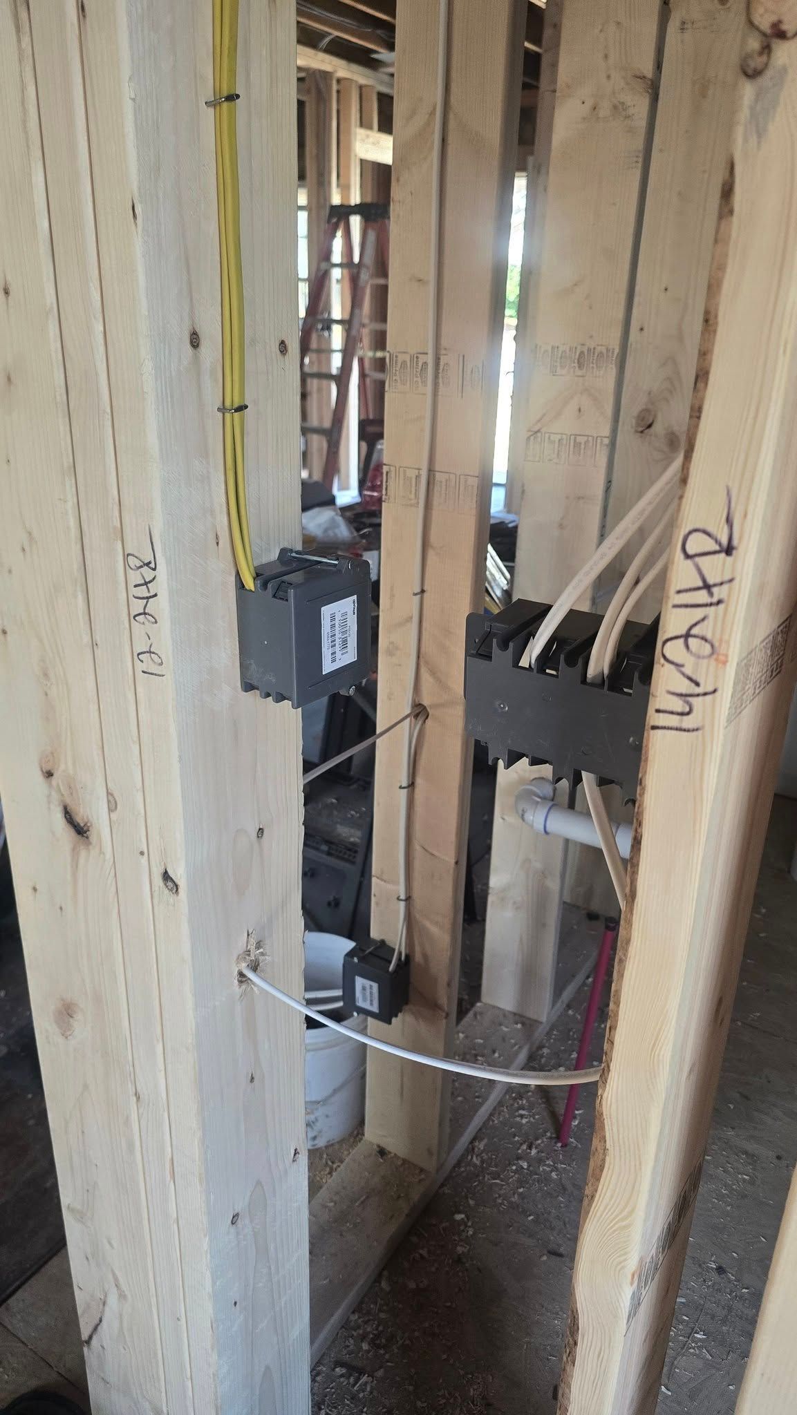 Electrical boxes and wiring installed between wooden studs in a new construction setting.