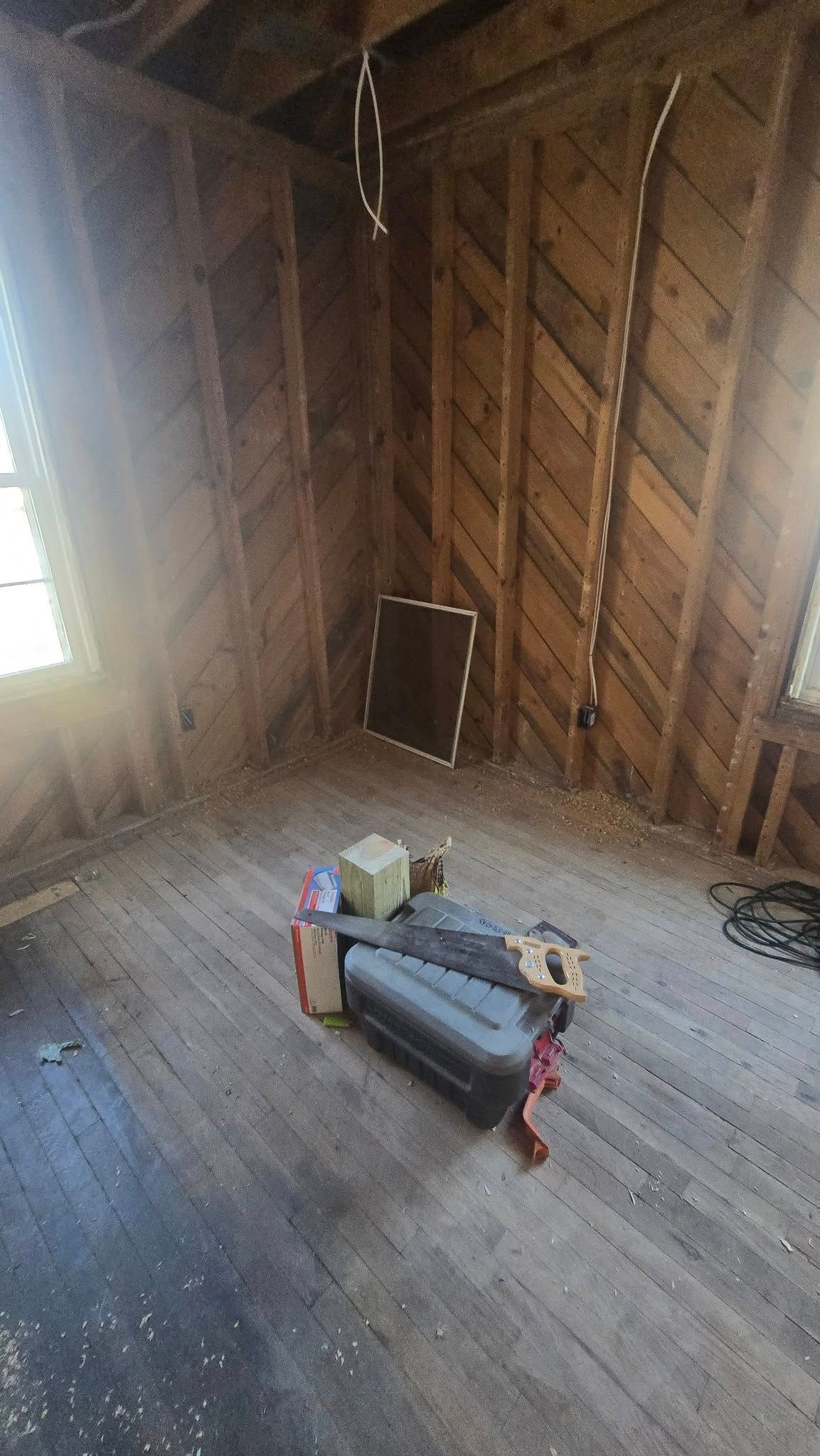 Dilapidated room: wood paneling, debris on floor, window, and a discarded couch.