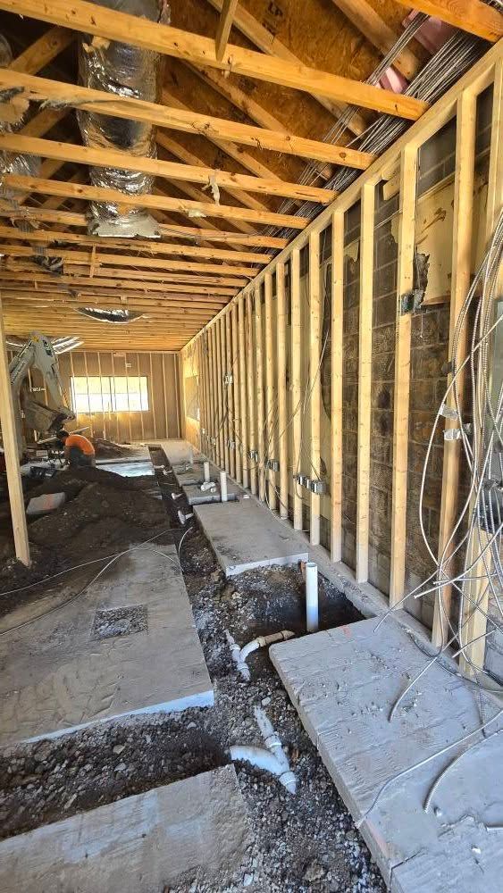 Interior view of a building under construction. Studs and plumbing visible.