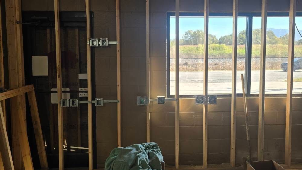 Interior construction with wooden studs, electrical boxes, window, and door frame.