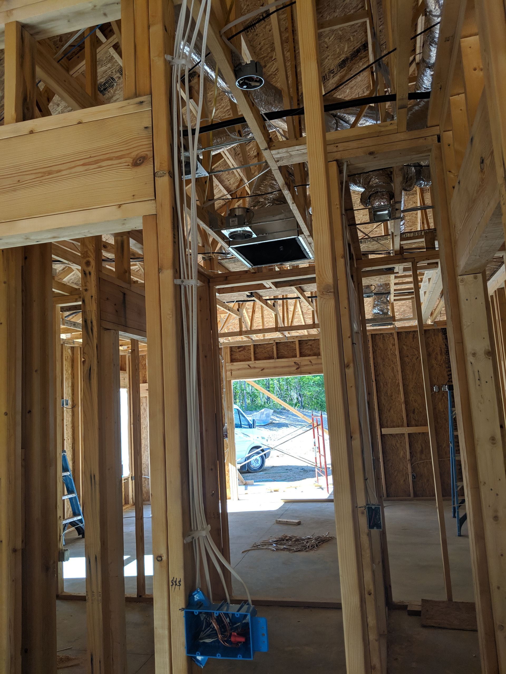 Interior view of a building under construction. Wood framing with electrical wiring and an open doorway.