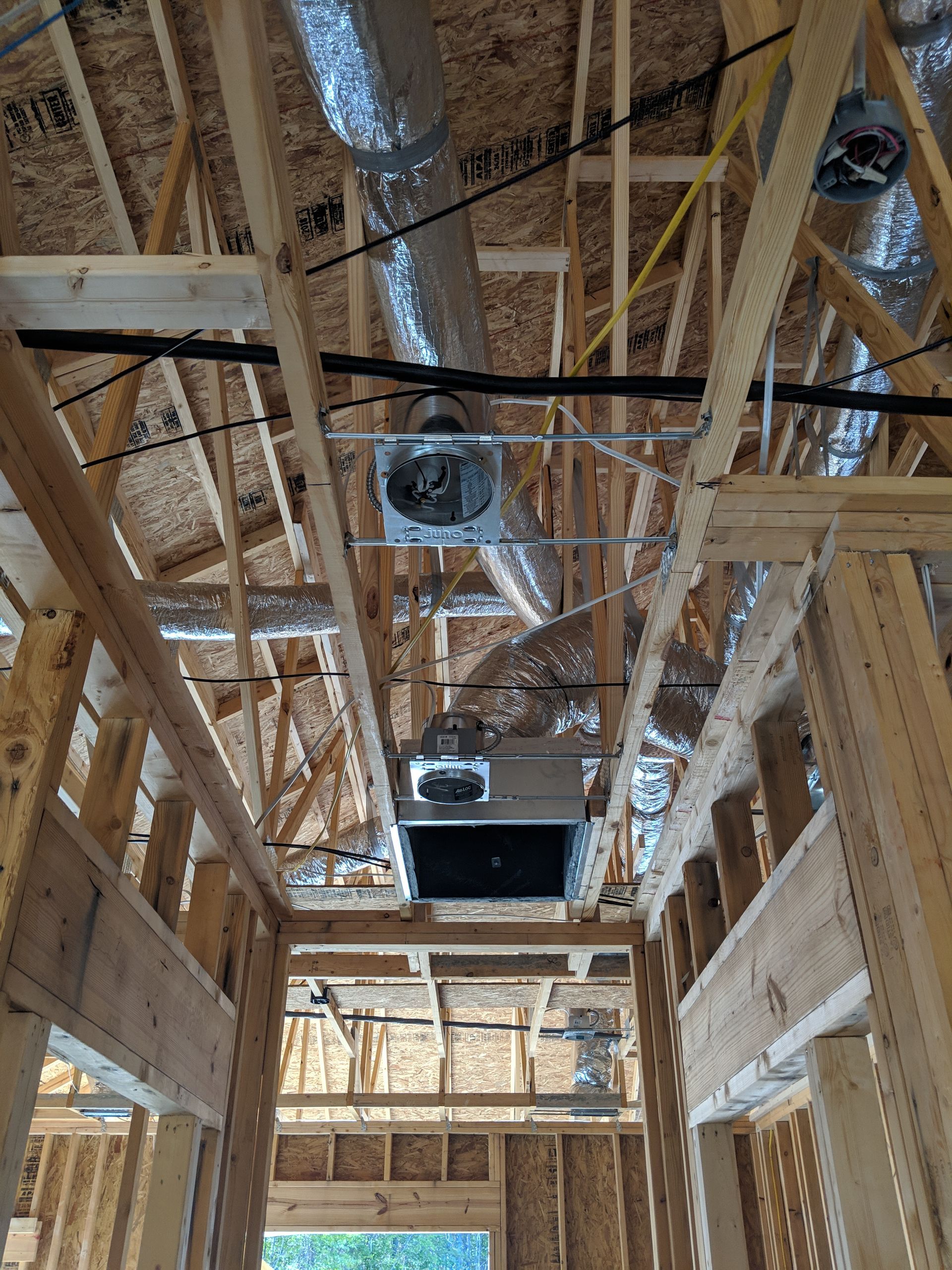 Interior view of unfinished wood framing with HVAC vents and ductwork installed.