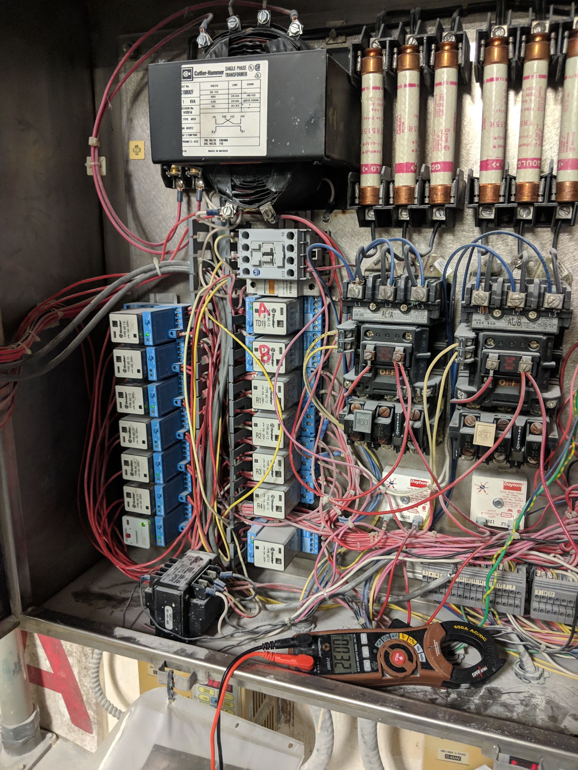 Electrical control panel with wires, relays, and fuses.