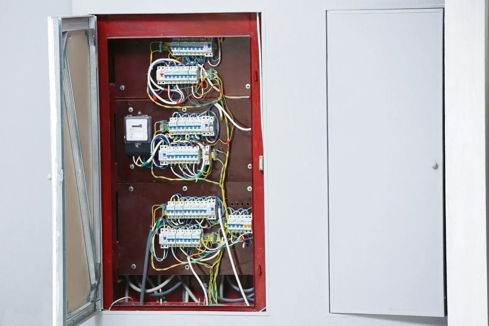 Red electrical panel with multiple circuit breakers and wiring.
