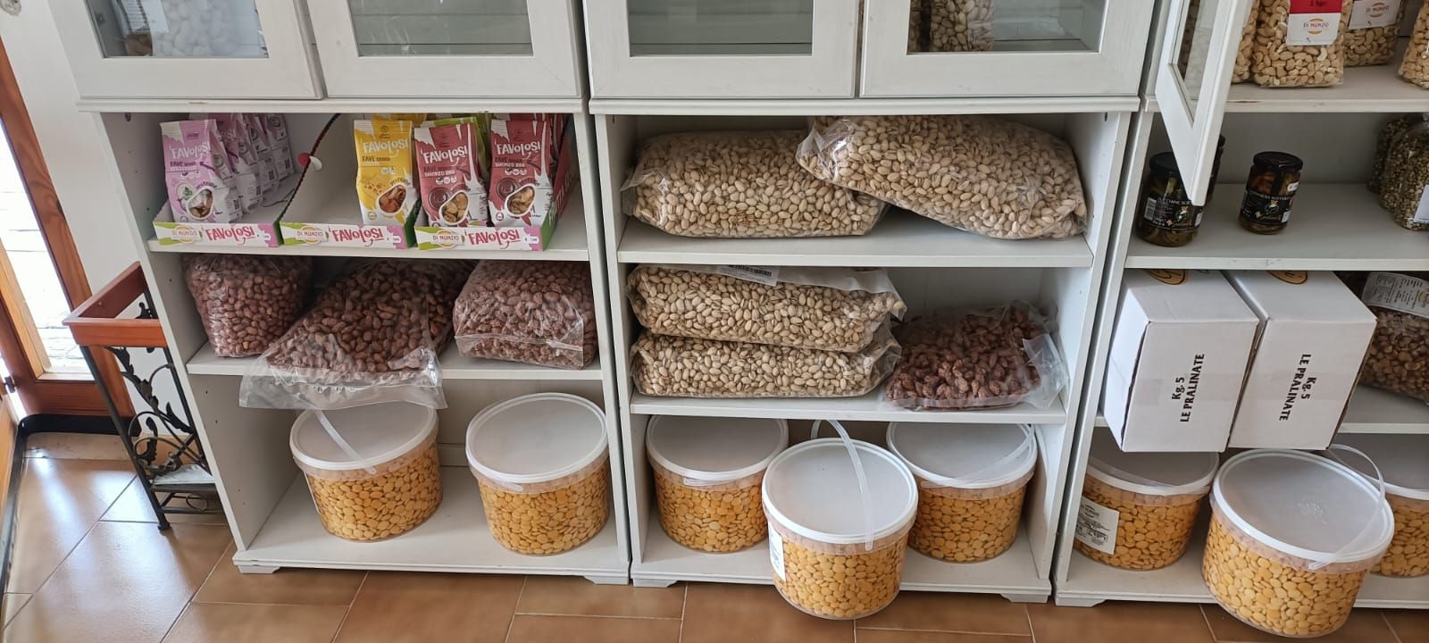 Scaffali della cucina con cestini e contenitori per cibo per animali, giocattoli e accessori, organizzati sotto i pensili.