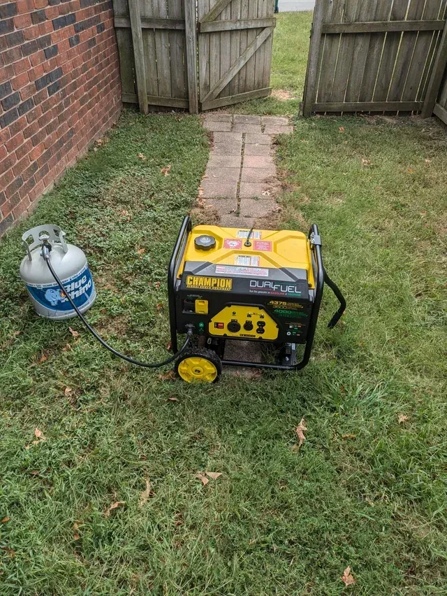 A large gray and black generator is parked on a sidewalk.