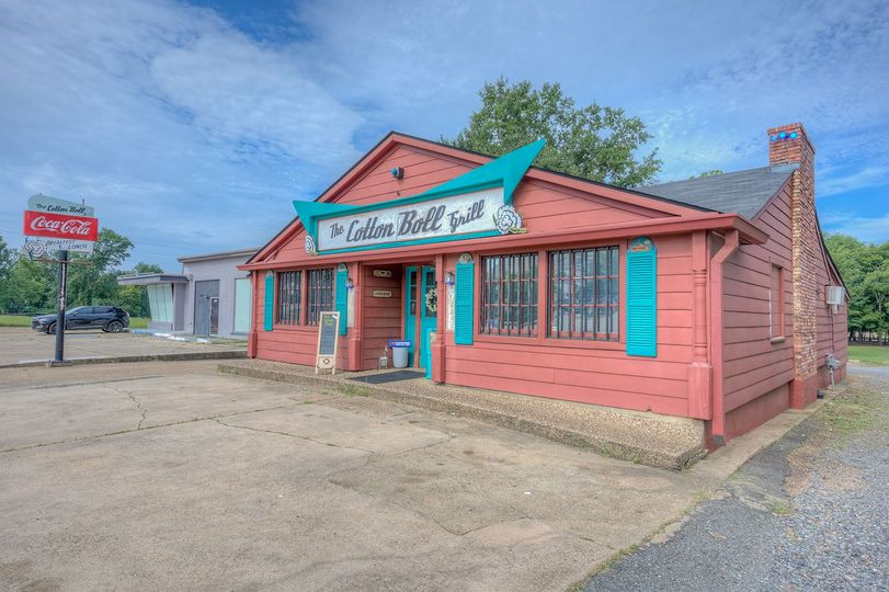 A red building with blue shutters and a coca cola sign in front of it.