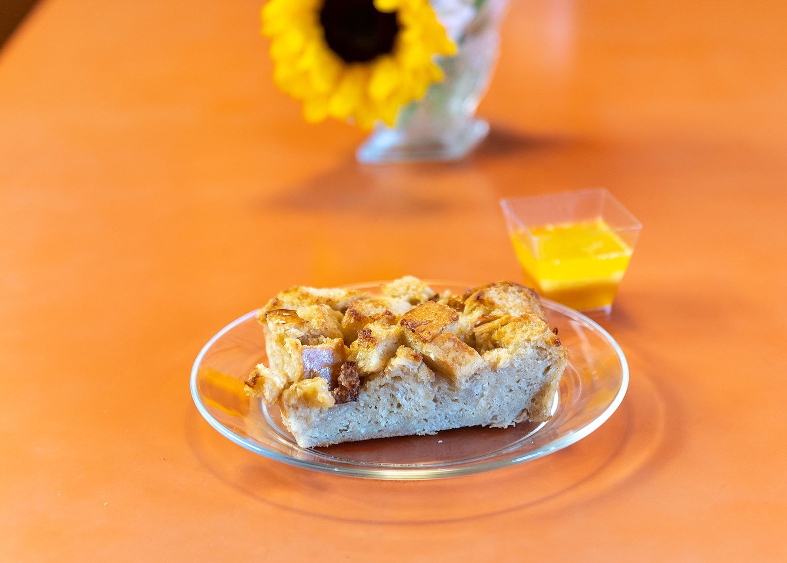 A piece of bread is on a glass plate on a table.