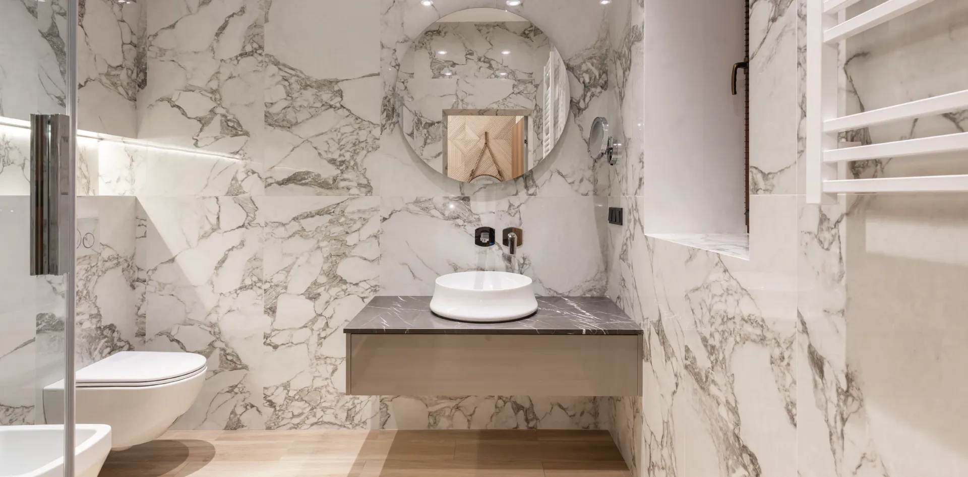 une salle de bain avec murs en marbre, lavabo, toilettes et douche.