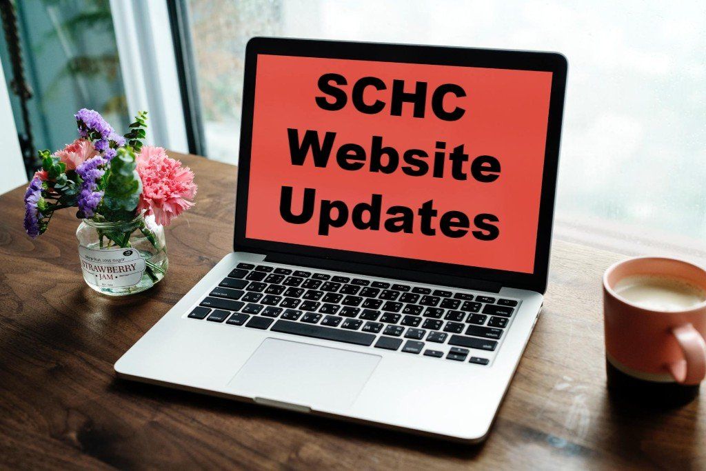 A laptop is open to a screen that says schc website updates