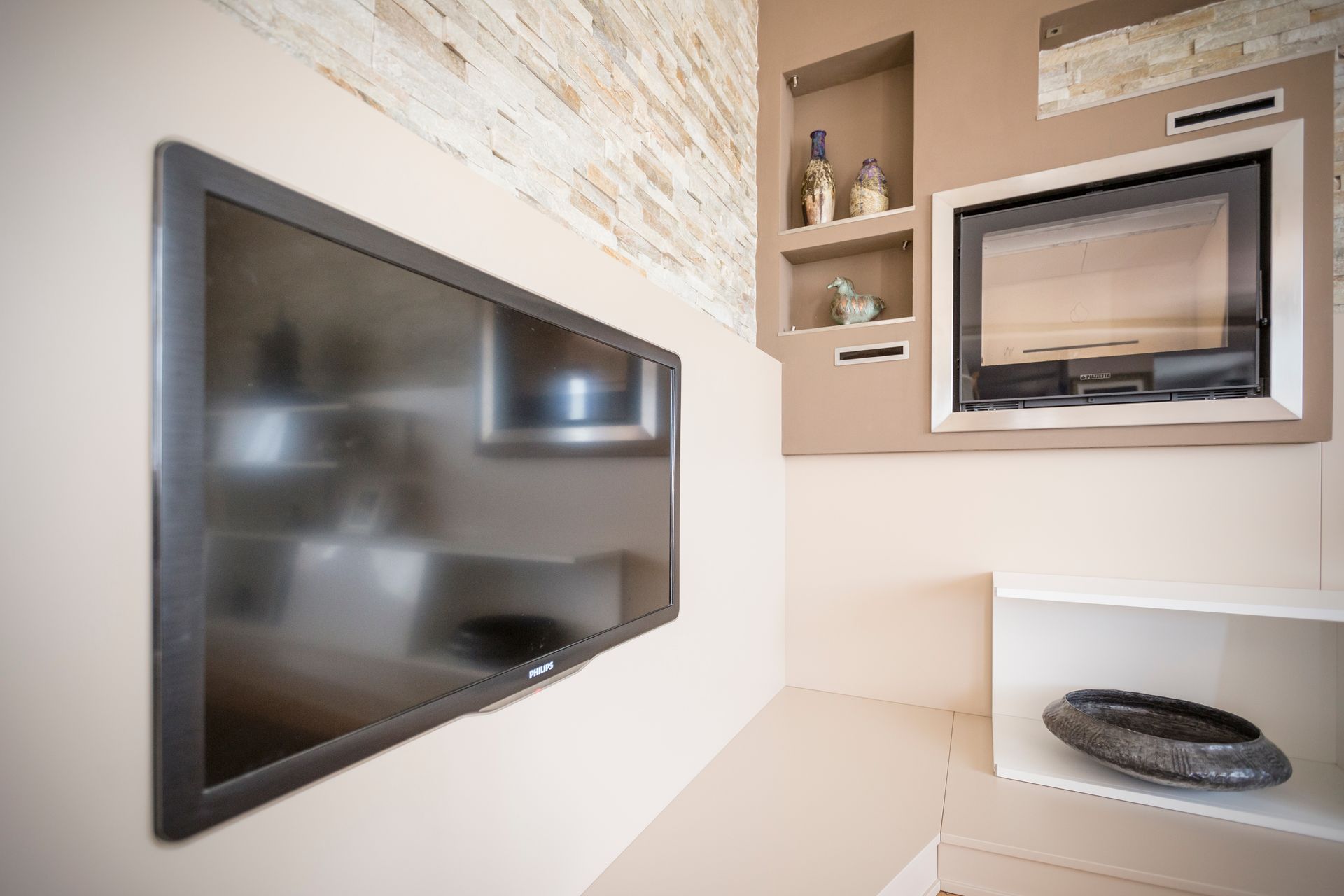 Una TV a schermo piatto è montata su una parete accanto a un camino.