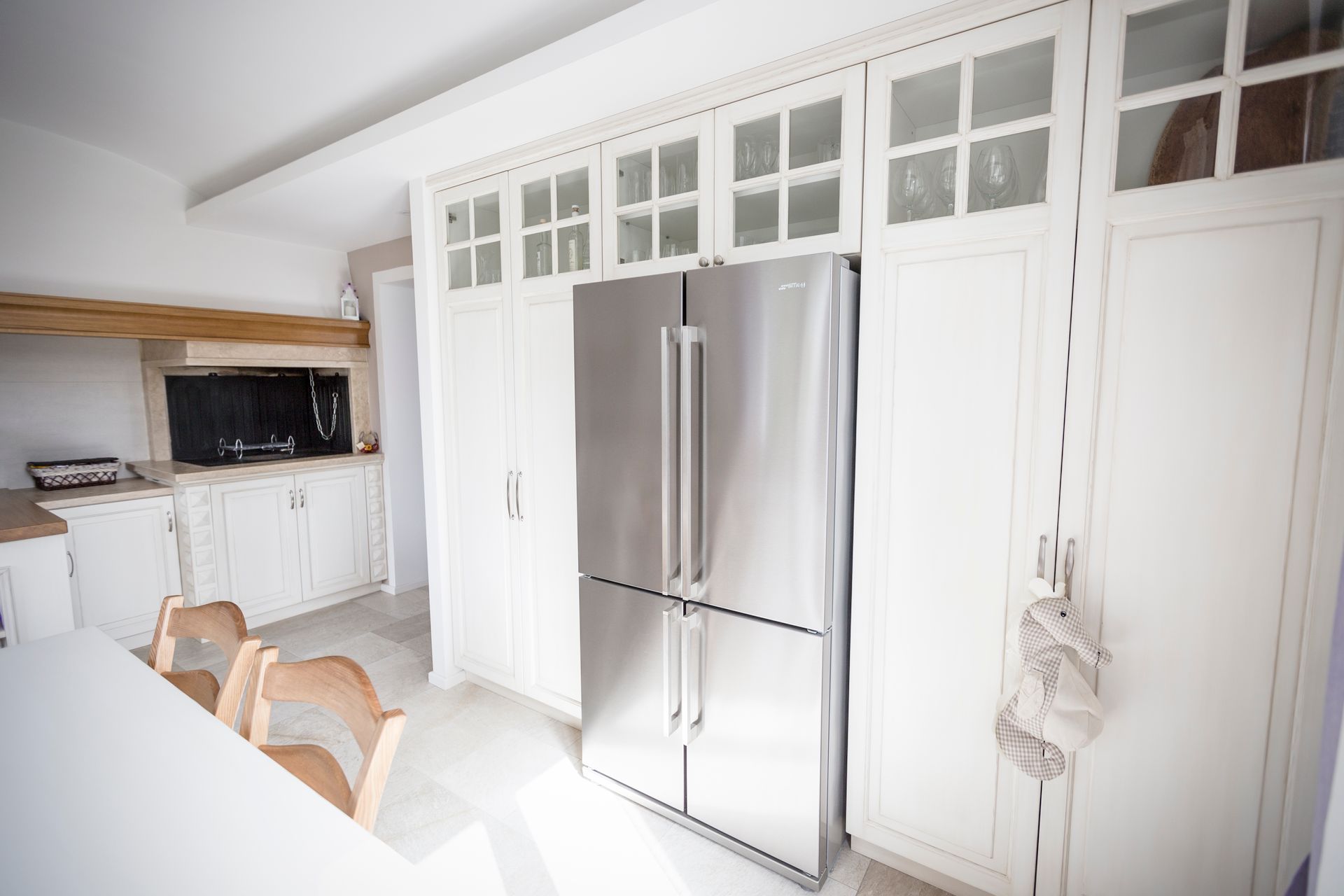 Una cucina con mobili bianchi e un frigorifero in acciaio inox