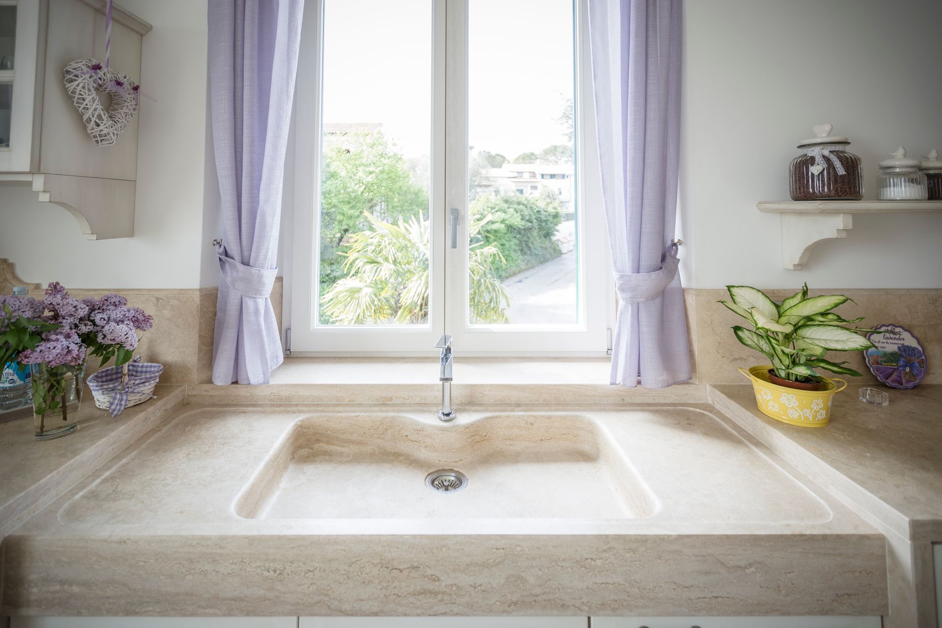 Una cucina con un lavandino e una finestra con tende viola.